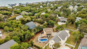Un quartier résidentiel où les maisons sont entourées d’arbres, avec une piscine et une vue sur l’océan.