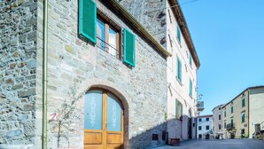 A stone building with a wooden door and green shutters, a potted plant, and a clear sky. - Stunning private villa for 4 people with hot tub, WIFI, A/C, TV, terrace and panoramic view (Seggiano)