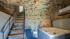 A stone-walled room with a wooden staircase, a hot tub, and a blue chair. - Stunning private villa for 4 people with hot tub, WIFI, A/C, TV, terrace and panoramic view (Seggiano)