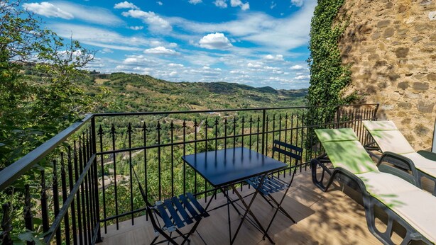 A balcony with a table and chairs, overlooking a scenic landscape with hills and a clear sky. - Stunning private villa for 4 people with hot tub, WIFI, A/C, TV, terrace and panoramic view (Seggiano)