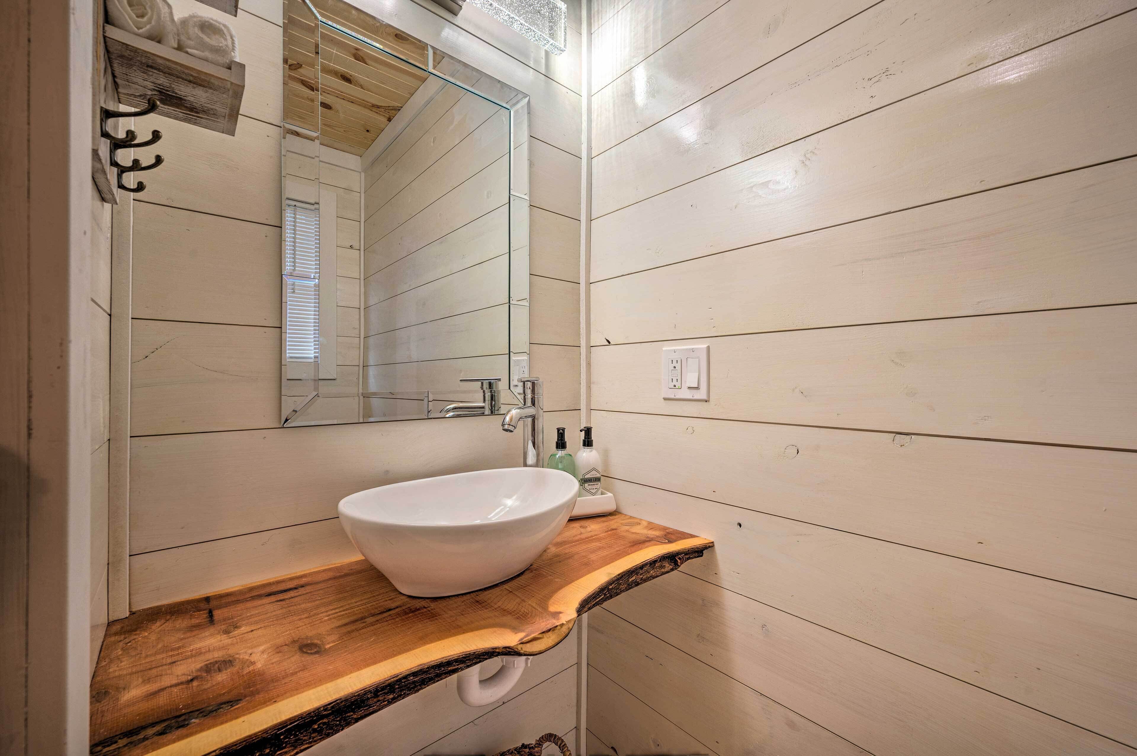A bathroom with a wooden vanity, a white sink, and a mirror.