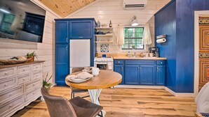 A kitchen with blue cabinets, a wooden ceiling, and a dining area with a table and chairs. - Romantic Broken Bow Cabin w/ Jacuzzi & Fire Pit! (Broken Bow)