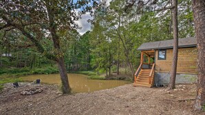 A rustic cabin with a wooden exterior, a porch, and a small staircase leading to the entrance. - Romantic Broken Bow Cabin w/ Jacuzzi & Fire Pit! (Broken Bow)