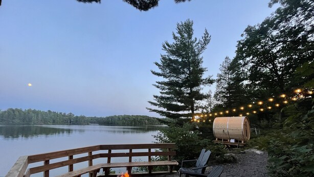 A wooden deck with a fire pit, outdoor seating, and string lights.
