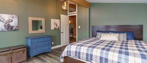 A bedroom with a bed, dresser, and a suitcase.