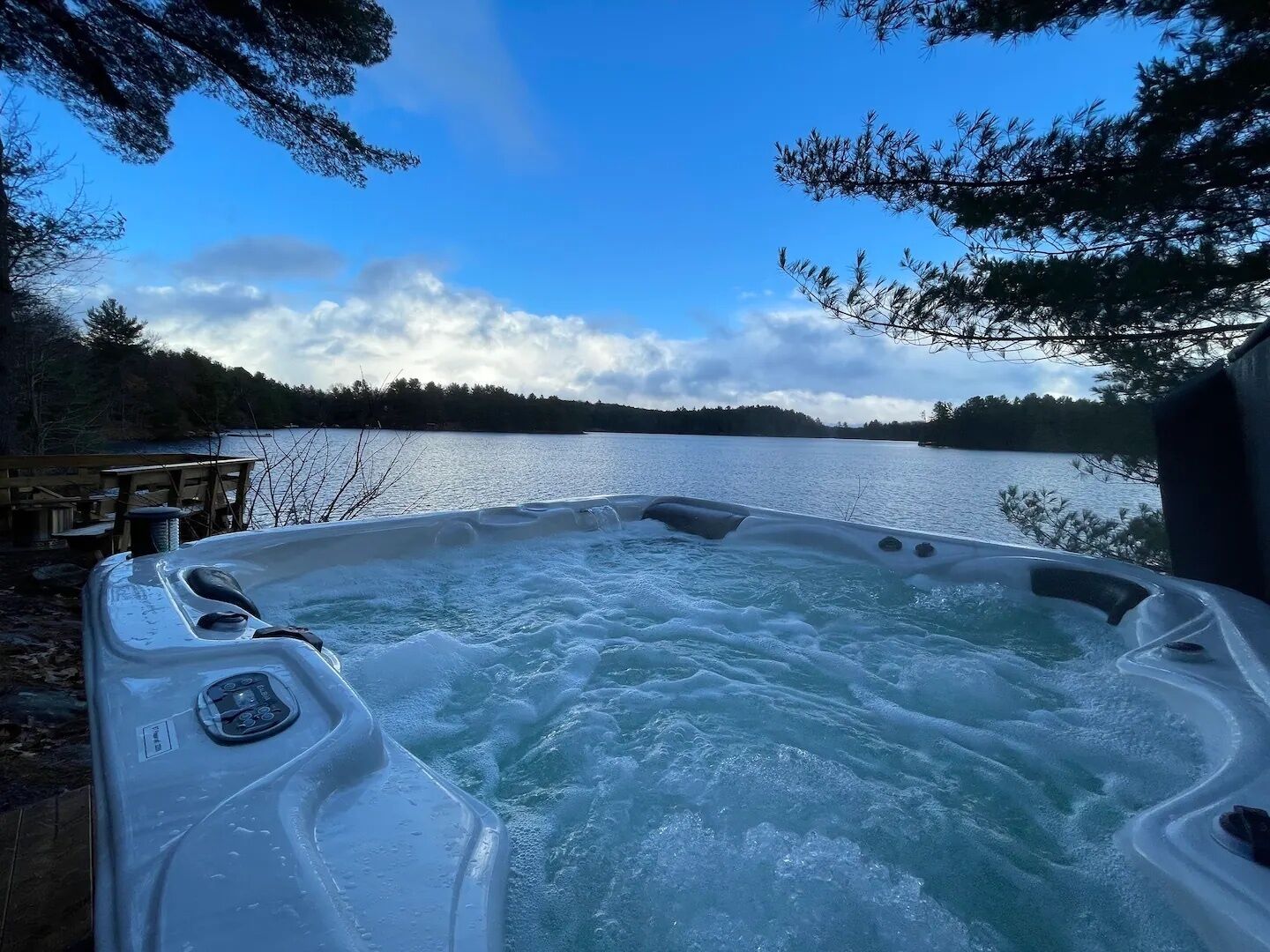A hot tub with a view of a lake and forest.