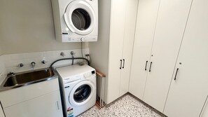 A laundry room with a washing machine, a dryer, and a sink.