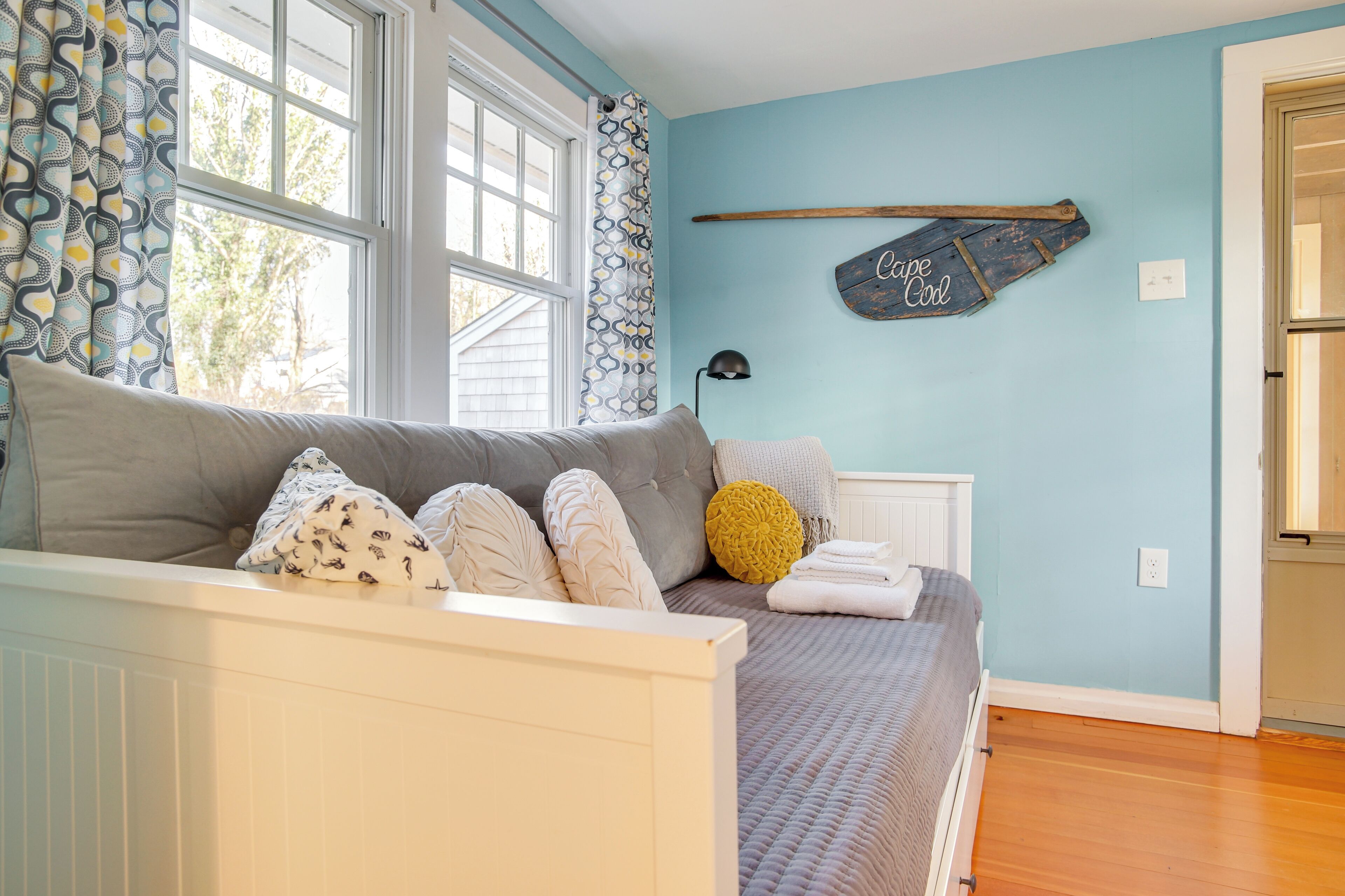 A bedroom with a bed, a window, a wall-mounted shelf, and a door.