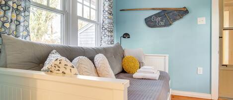 A bedroom with a bed, a window, a wall-mounted shelf, and a door.