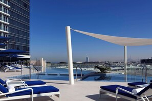 Un área de piscina en la azotea con sillones y vistas del horizonte de la ciudad.