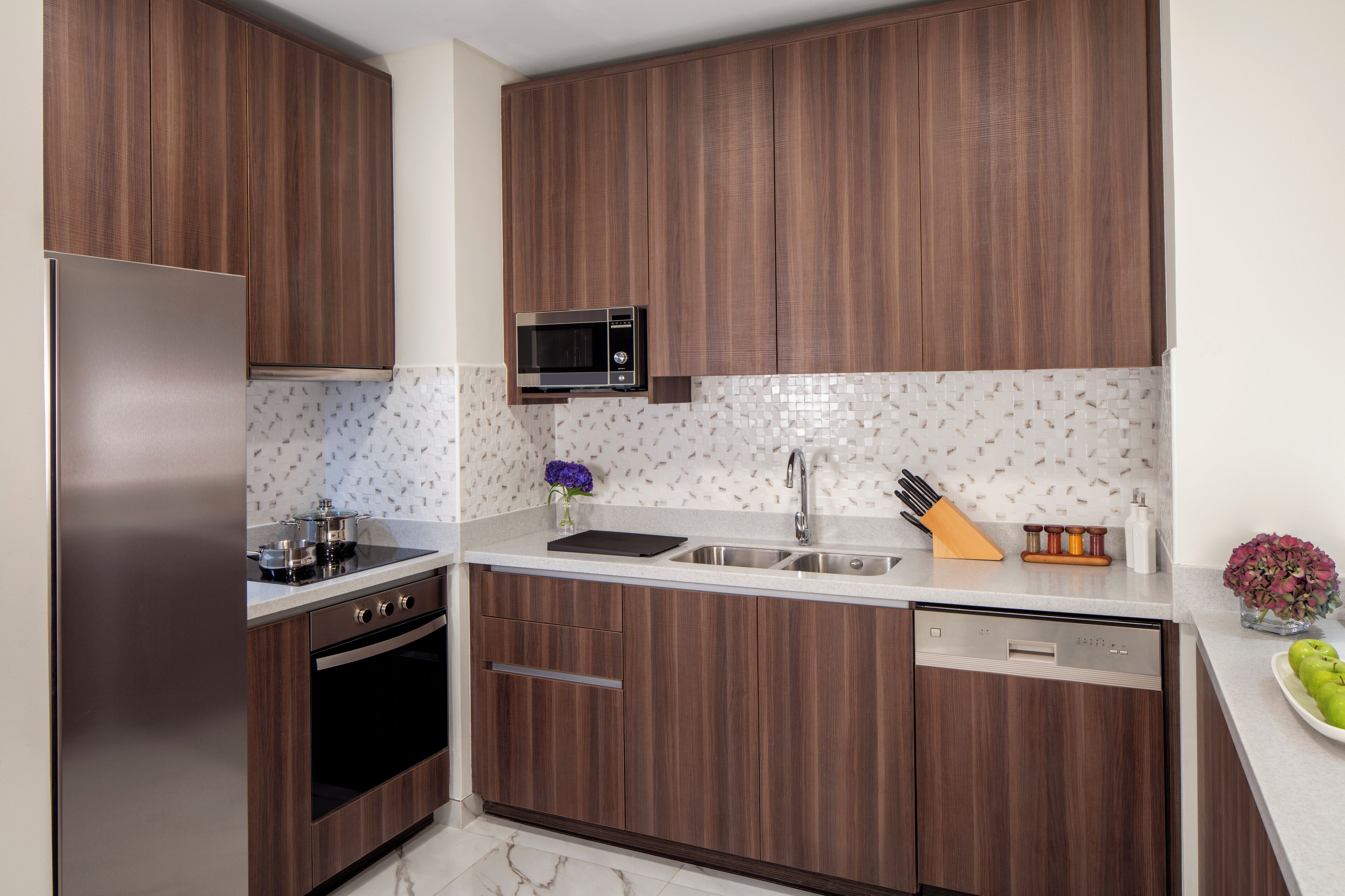 A modern kitchen with wooden cabinets, stainless steel appliances, and a tiled backsplash.
