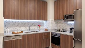 A modern kitchen with wooden cabinets, stainless steel appliances, and a patterned backsplash.