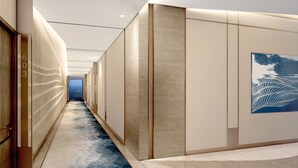 Un pasillo moderno con suelo de diseño geométrico, un cuadro abstracto grande en la pared derecha y una puerta con el número 603 a la izquierda.