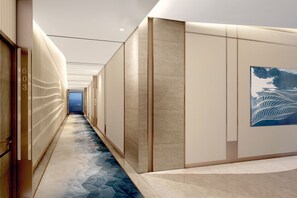 A modern hallway with a geometric patterned floor, a large abstract painting on the right wall, and a door with the number 603 on the left. - Avani+ Palm View Dubai Hotel & Suites (Dubai)
