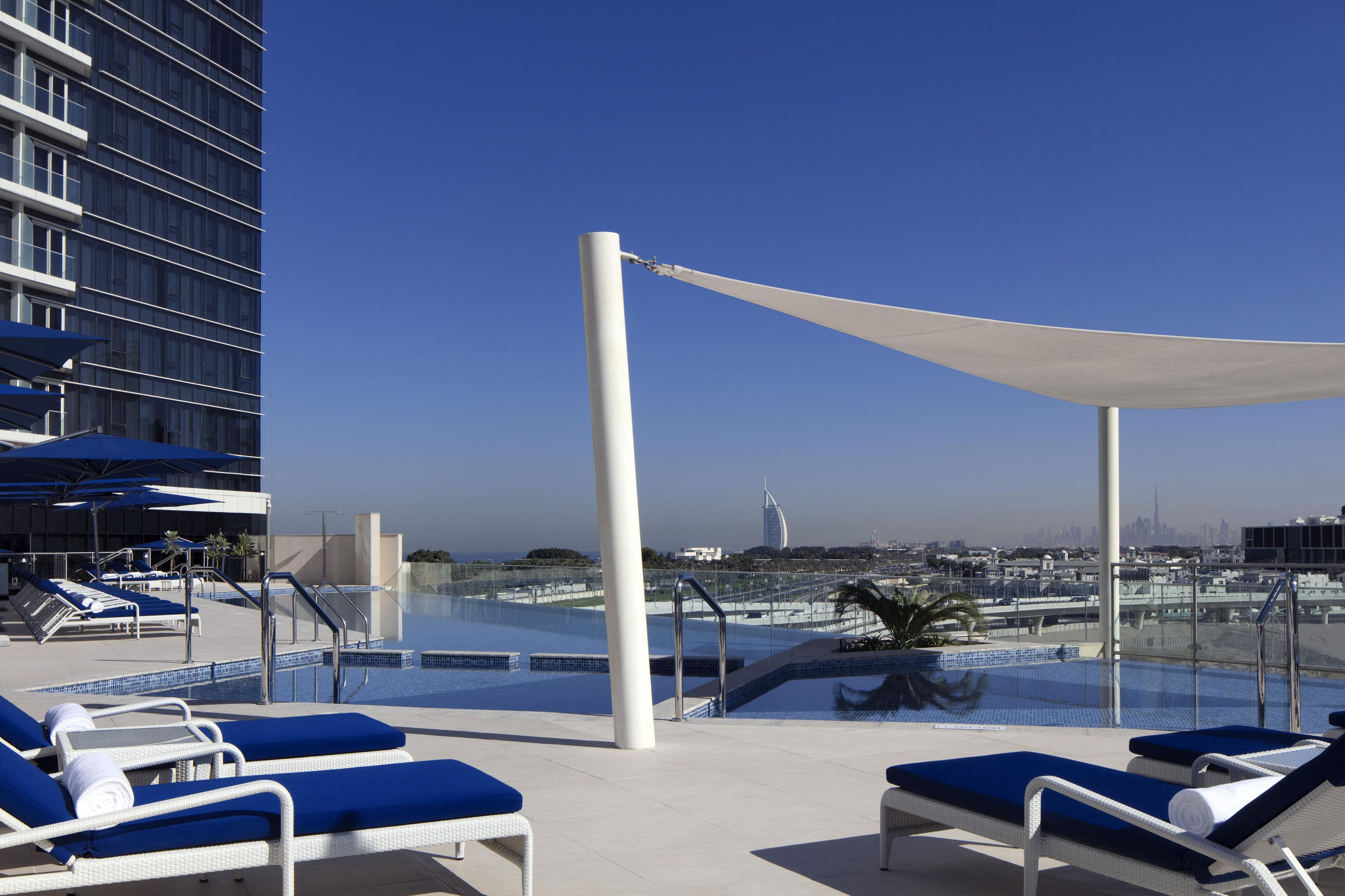 A rooftop pool area with lounge chairs and a view of the city skyline.