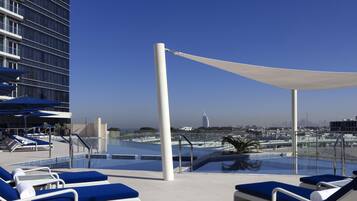 A rooftop pool area with lounge chairs and a view of the city skyline.