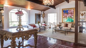 A spacious living room with a large ornate table, multiple seating areas, and a chandelier. - Single room in a luxury hotel. (RJ)