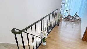 Een trap met een metalen leuning, een bloempot en een houten vloer.