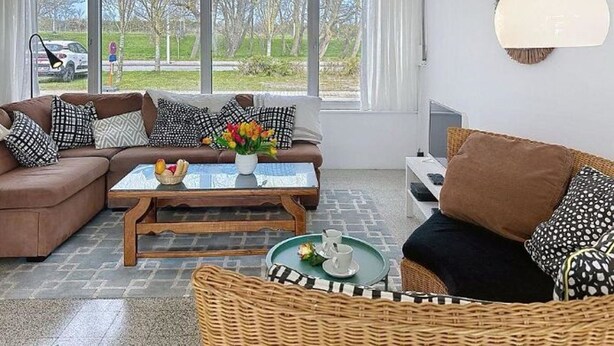 Een moderne woonkamer met een bank, een salontafel en een rieten fauteuil.