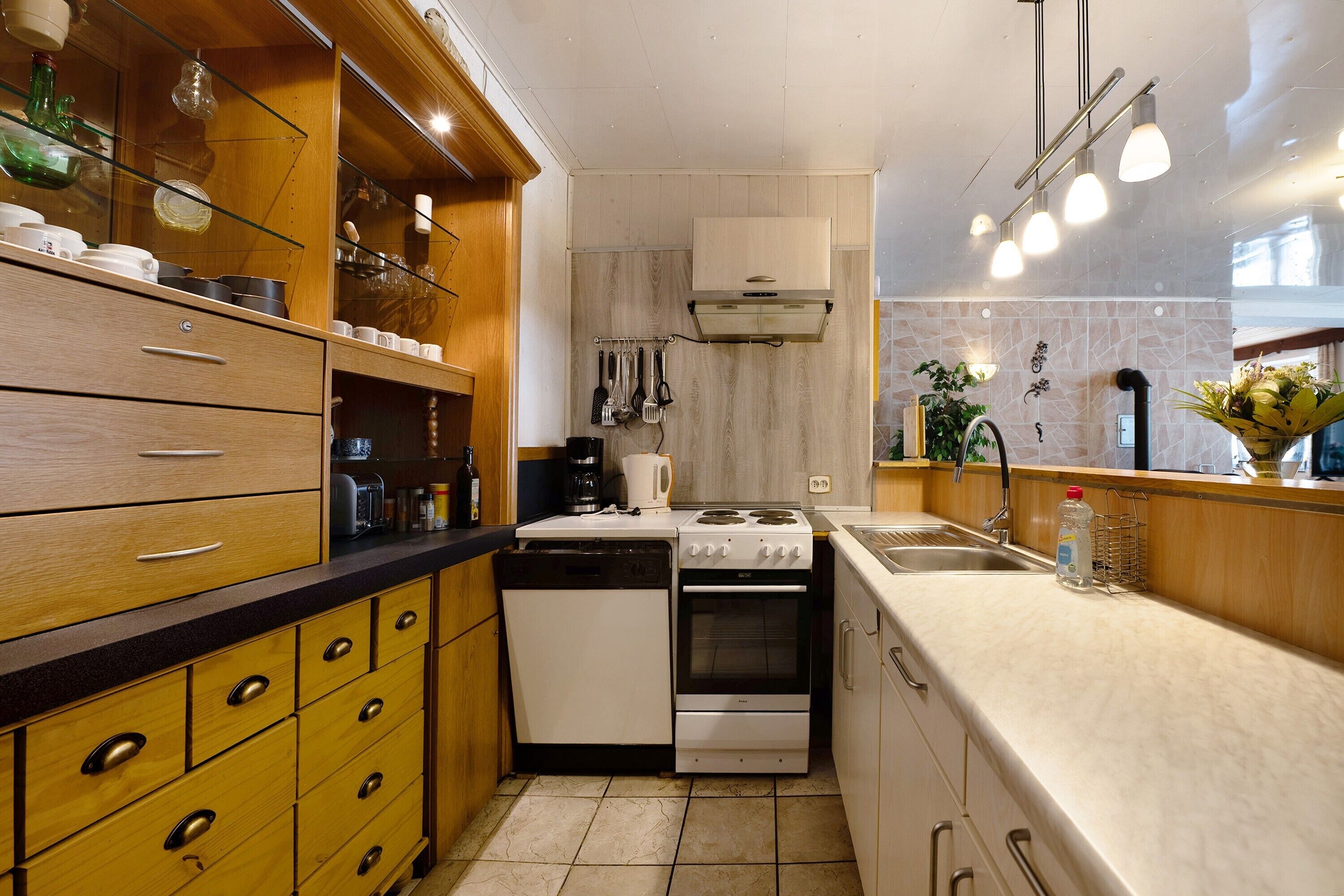 A compact kitchen with wooden cabinets, a stove, oven, and a sink.