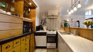 A compact kitchen with wooden cabinets, a stove, oven, and a sink.