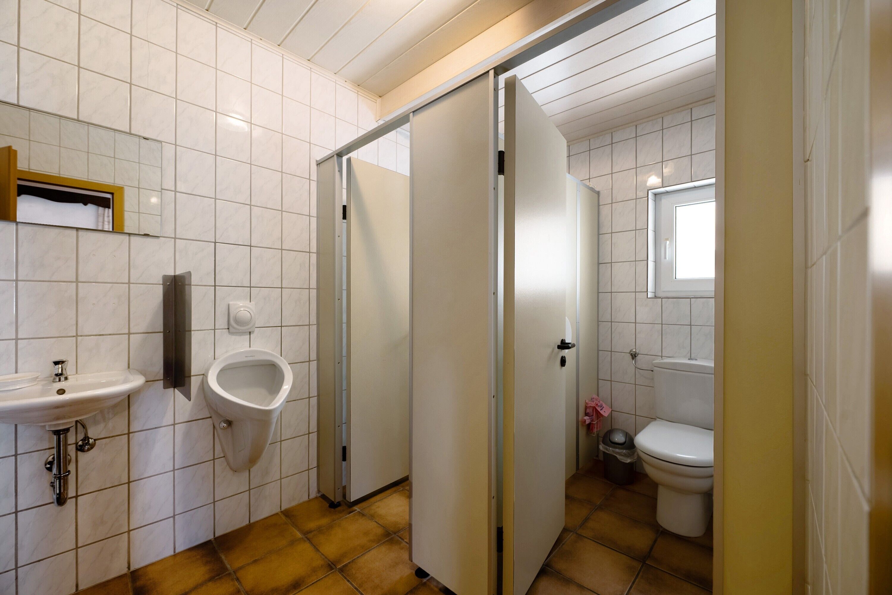 Une salle de bain équipée d’un lavabo, d’un urinoir, de toilettes et d’une porte coulissante.
