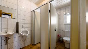 Une salle de bain équipée d’un lavabo, d’un urinoir, de toilettes et d’une porte coulissante.