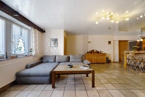Un salon comprenant un canapé d’angle, une table basse et un coin repas avec des chaises.
