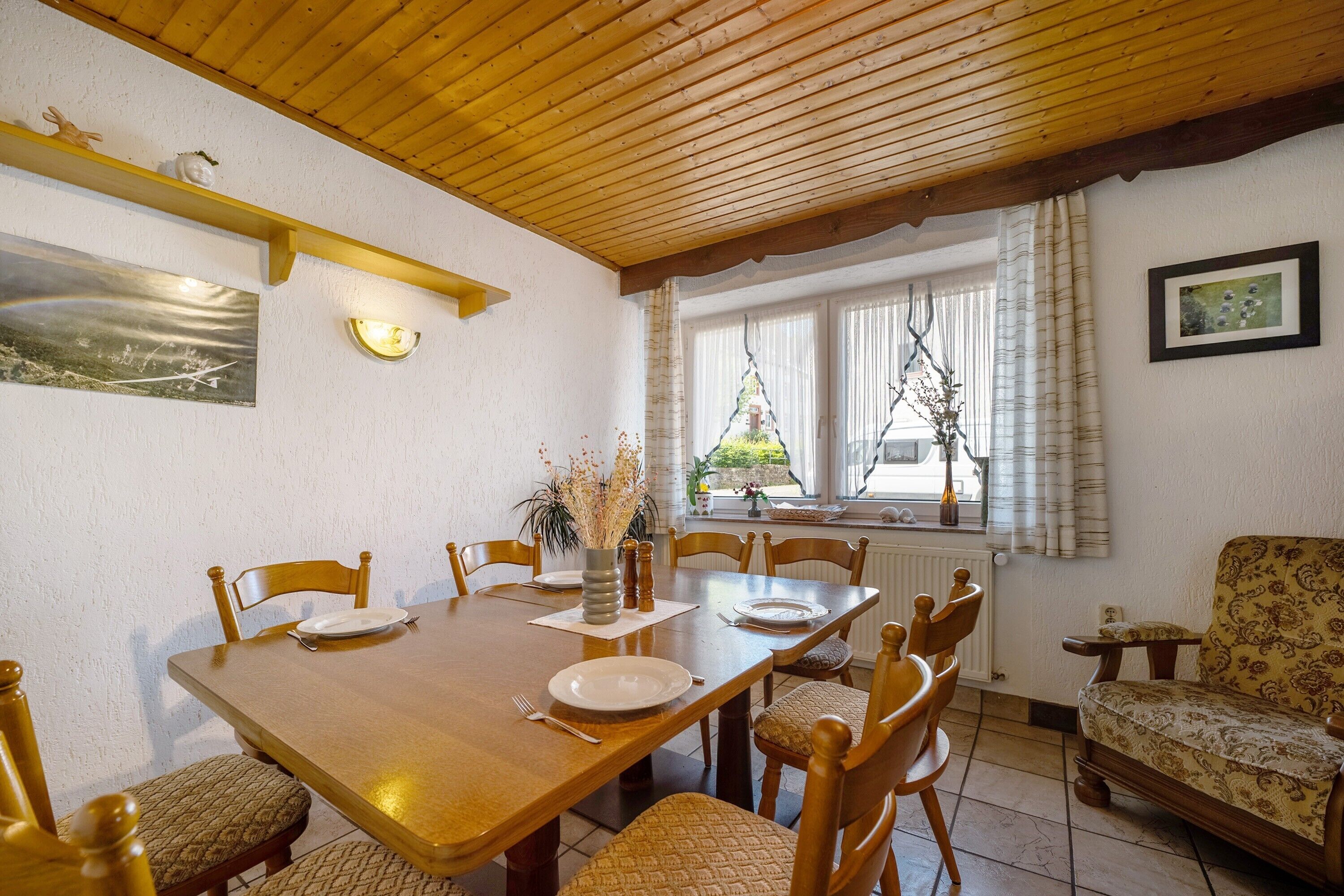 Ein Essbereich mit Holztisch, Stühlen und einem Fenster mit Vorhängen.