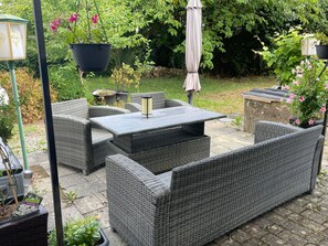 An outdoor patio area with wicker furniture, a table, and hanging planters.