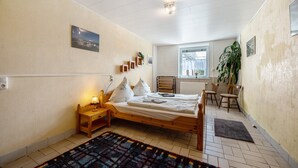 A bedroom with a wooden bed, bedside table, lamp, and a view of the outside. - Vacation Apartment "Wiesental" with Wi-Fi, Wood-Burning Stove & Shared Garden (Meisburg)