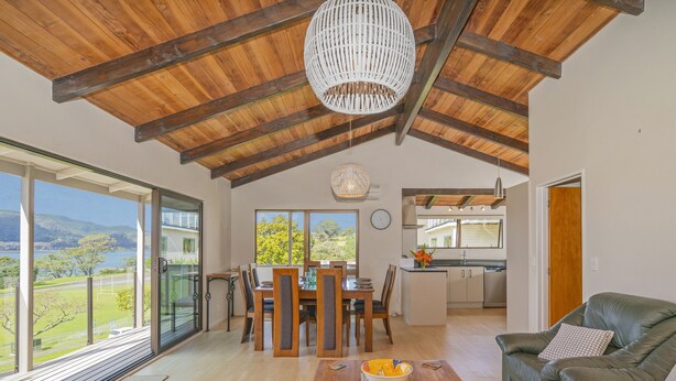 A spacious living area with a dining table, a sofa, and a kitchen in the background.