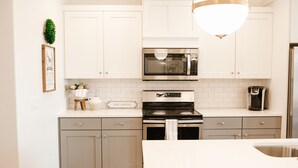 Eine moderne Küche mit weißen Schränken, einer Edelstahl-Mikrowelle und einem eingebauten Backofen.