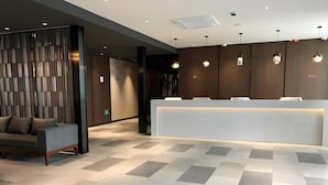 A modern reception area with a check-in counter, a sofa, and a patterned floor. - Jinjiang Inn Select (Shanghai)