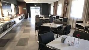 A modern hotel dining area with a long counter, multiple tables, and chairs. - Jinjiang Inn Select (Shanghai)