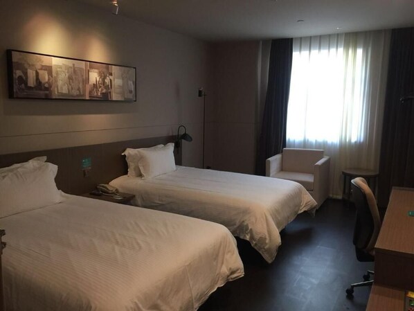 A hotel room with two beds, a desk, a chair, and a large window with curtains. - Jinjiang Inn Select (Shanghai)