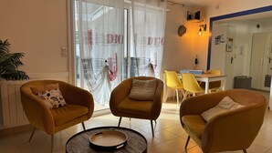 Una sala de estar moderna con dos sillones amarillos, una mesa de centro redonda y un comedor con sillas amarillas y una mesa.