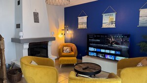 Una sala de estar con televisor, sillones amarillos, chimenea y pared azul.