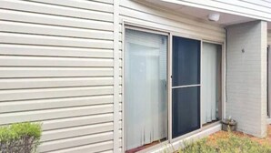A house with a sliding glass door, a small garden area, and a number '6' on the wall.