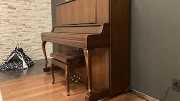 Een vleugelpiano in een ruimte met een stenen muur en een houten vloer.