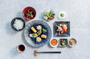 Variedad de platos japoneses, como sushi, arroz y sopa, dispuestos sobre una mesa.