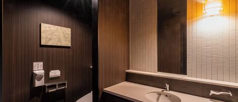 A modern bathroom with a wooden vanity, a toilet, and a wall-mounted sink.