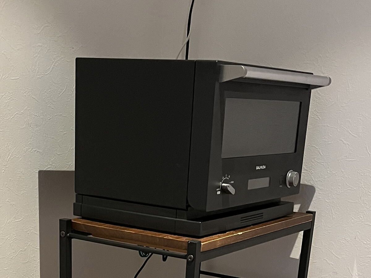 Ein schwarzer Fernseher auf einem Holzboden vor einer strukturierten Wand.