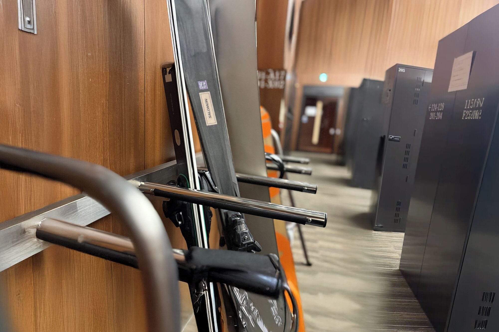 A row of lockers with metal bars and a wooden floor.