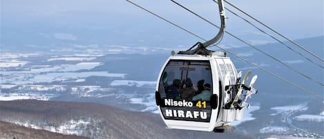 A cable car with passengers, labeled "Niskeo 41" and "HIRAFU," moving along a cable.