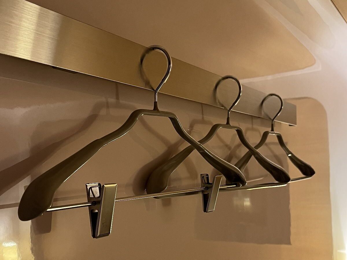A wall-mounted coat rack with four metal hangers.