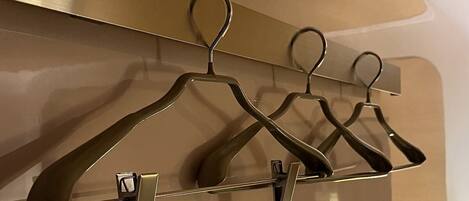 A wall-mounted coat rack with four metal hangers.