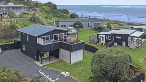A modern residential area with houses, a grassy yard, and a view of the ocean. - Raglan Beach House , Stunning Ocean and Harbour views out at  Ocean Beach (Raglan)