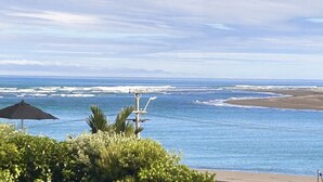A coastal view with a beach, ocean waves, and a clear sky. - Raglan Beach House , Stunning Ocean and Harbour views out at  Ocean Beach (Raglan)