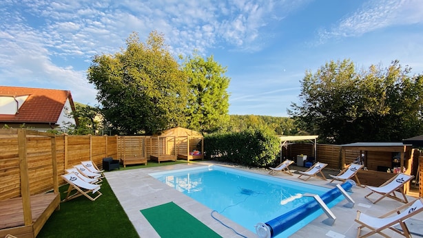 A backyard with a swimming pool, lounge chairs, and wooden structures. - Pension Günther (Graz)